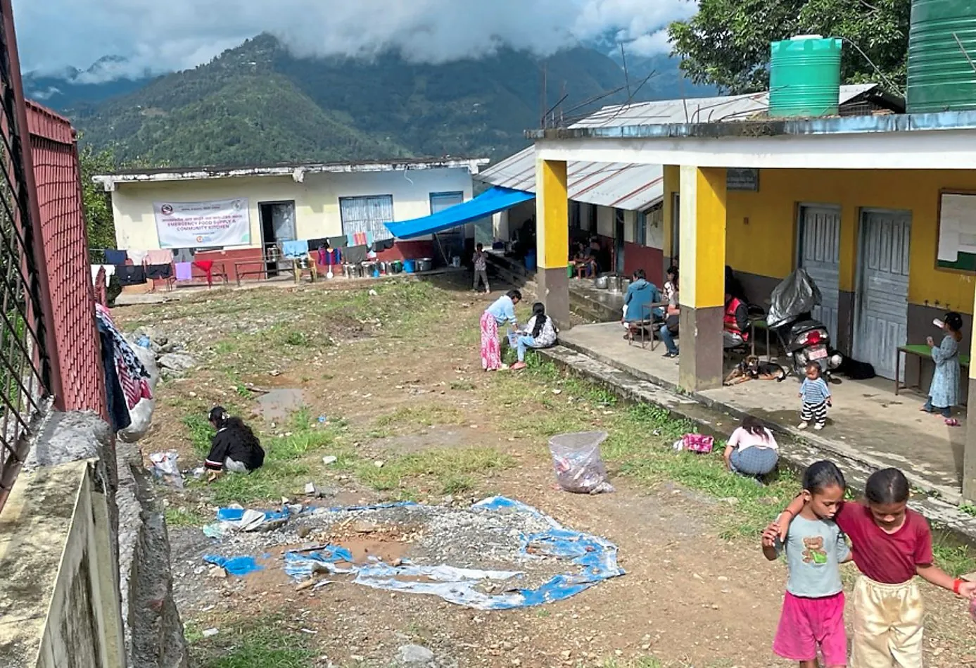 Menschen im Flutgebiet in Nepal Kinder und Erwachsene im Hof zwischen Gebäuden in einer Bergregion Nepals.